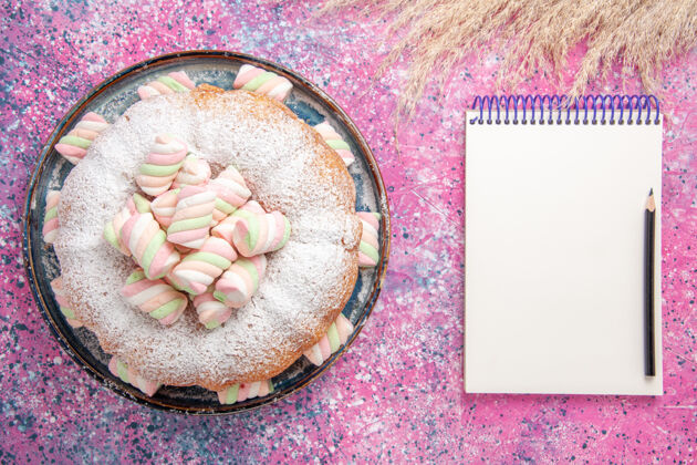 美味糖粉蛋糕的俯视图 粉色表面有甜棉花糖和记事本质地饼干含糖