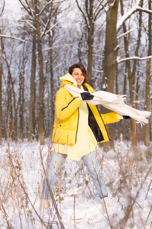 可爱美丽的年轻开朗的女人在雪景的冬日森林里玩得很开心 穿着暖和的衣服在冬天和雪里快乐霜冻爱节日