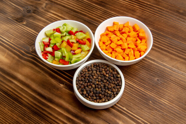 顶部顶视图不同调味料的甜椒片放在棕色木桌上蔬菜一餐食品健康沙拉晚餐胡椒粉午餐