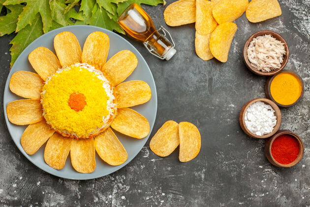 叶子深灰色桌子上沙拉的顶视图 旁边放着油瓶脆薯片和叶子 旁边放着香草饮食油柑橘