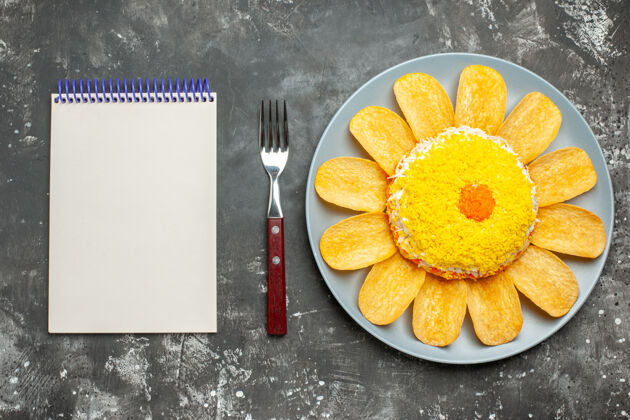 左边黑色背景下 从左侧看到沙拉和薯片 叉子和记事本的俯视图薯条柑橘早餐