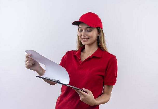 交货面带微笑的年轻送货女孩穿着红色制服 戴着帽子 拿着白色的纸片翻着表情翻转年轻
