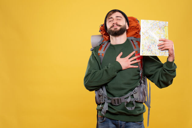 心旅行概念与梦想年轻人与背包和举行地图把他的心放在黄色的手年轻人漂亮成人
