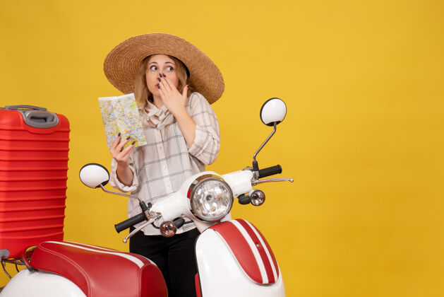 轮廓顶视图困惑的年轻女子戴着帽子收集她的行李坐在摩托车上拿着地图年轻女子帽子坐