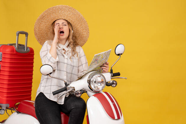 年轻女子顶视图年轻女子戴着帽子 坐在摩托车上 拿着地图叫着黄色的人比赛高尔夫摩托车