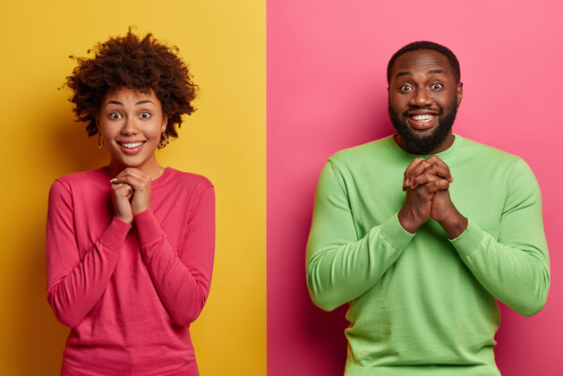 关系很高兴美国黑人女朋友和男朋友手牵手祈祷 期待重要的结果 靠着两面彩色的墙站在一起 面带微笑 感到幸福在一起相信剃胡子