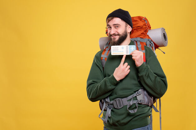 西装带着微笑的年轻人 背着背包 指着黄色的车票 旅行的概念旅行帅哥指点