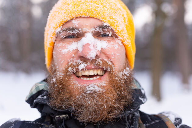 男一个留着胡子的男人的近照 所有的脸都在雪地里 在雪林里散步降雪度假