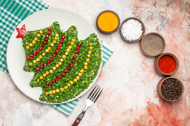 圣诞节顶视图美味的绿色沙拉在新年树形状与调味品在轻背景新的食物年