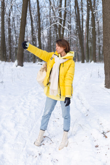 衣服年轻美丽快乐开朗的女子在冬季森林视频博客 自拍照片森林在线采取
