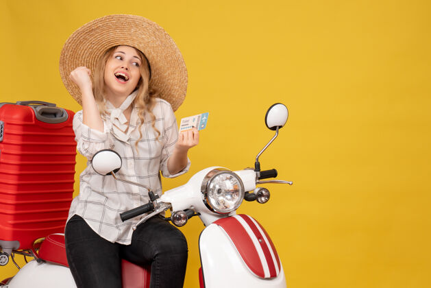 足球戴着帽子 坐在摩托车上 拿着黄色车票的快乐年轻女子的俯视图抱帽子足球