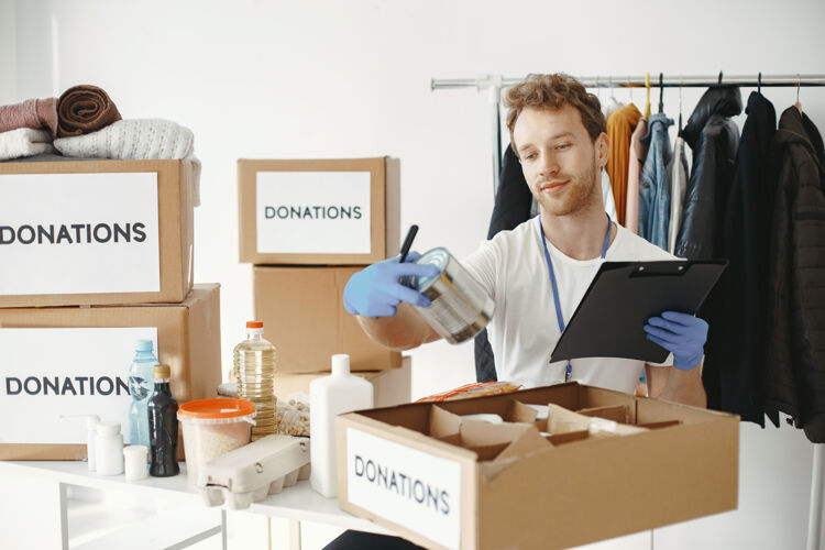 志愿者志愿者从捐款中收集东西男人用东西包装盒子男人比较捐赠人手册成人