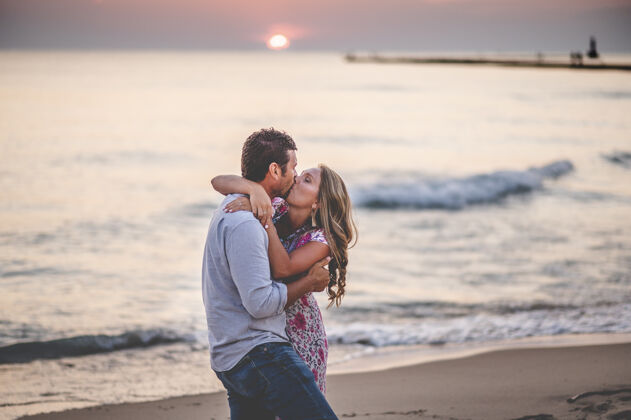 时尚一对年轻可爱的情侣在沙滩上亲吻的浅焦镜头优雅亲吻约会