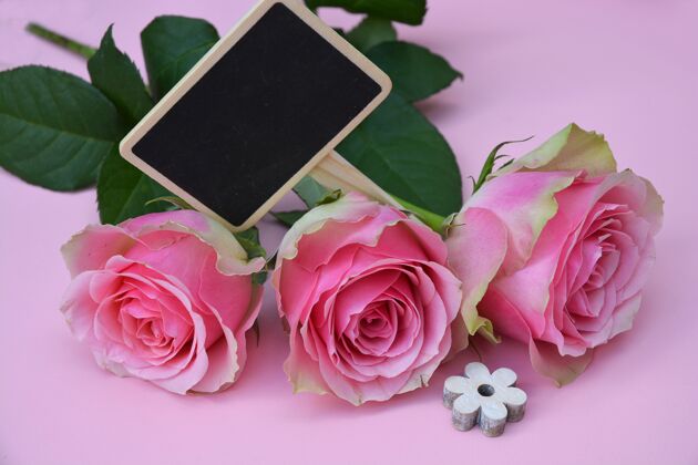 花蕾美丽的粉红色花朵与木制形状的花朵在粉红色的表面浪漫头花