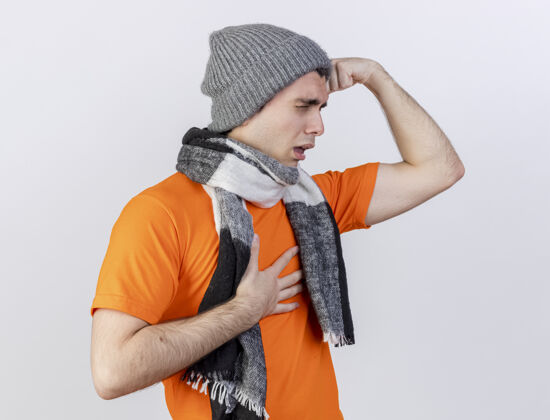 手站在侧视图上的年轻病人戴着冬天的帽子 戴着围巾 双手放在额头上 疼痛的胸部隔离在白色的背景上围巾站着疼痛
