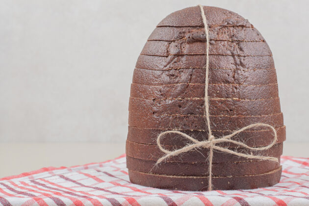 面包用绳子把新鲜的棕色面包片放在桌布上自然食品烘焙