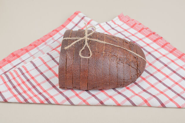 健康用绳子把新鲜的棕色面包片放在桌布上面包房一餐吐司