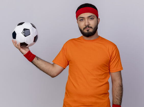 头带自信的年轻运动型男子戴着头带和腕带 在白色背景上孤立的一侧举着球球运动腕带