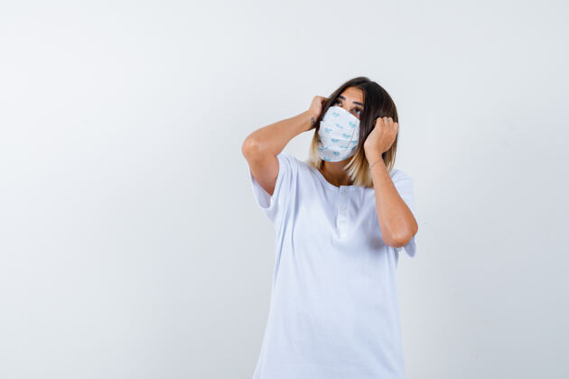 护理年轻的女性手举着t恤衫 戴着面具 看上去很体贴正面图健康亚洲人眼睛