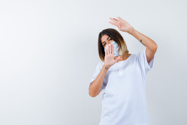 女人穿着白色t恤和面具的年轻女孩展示了四个手指的手势和停车标志 看起来很自信 正面视图肖像停止卷发