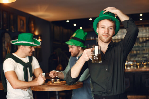 啤酒戴绿帽子的男人朋友们庆祝圣帕特里克节在酒吧庆祝马克杯啤酒男性