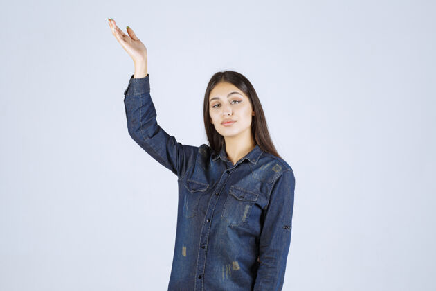 人类穿着牛仔衫的年轻女子举起双手 指着上面的东西姿势聪明工人