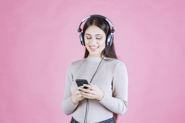 年轻人戴着耳机在智能手机前放音乐的年轻女人人类休闲女性