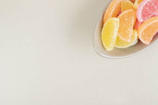 零食甜甜的彩色果冻糖果在米色的碗表面五颜六色邦邦切片