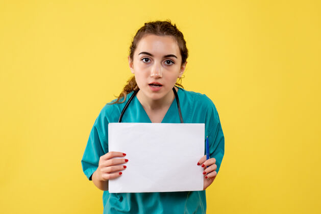 听诊器正面图：穿着医用衬衫的女医生拿着纸和听诊器 制服病毒大流行的covid-19纸张制服黄色