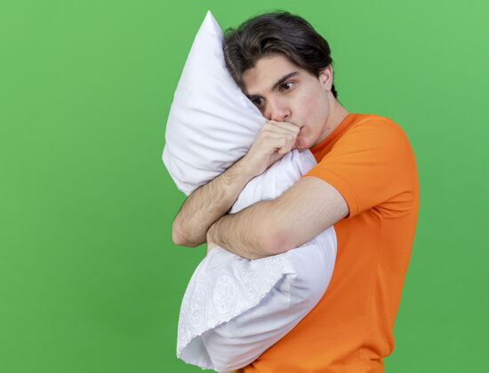 疾病看着身边年轻的病夫抱着枕头 手放在嘴上 隔离在绿色的背景上手嘴拥抱