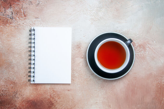 按钮从远处俯瞰一杯茶一杯茶在红碟白笔记本上马克杯茶