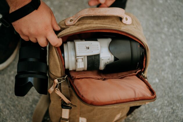 技术摄影师从相机包里拿出一个白色的相机镜头摄影师摄影设备
