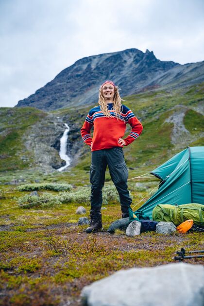 毛衣站在山上帐篷外的挪威人 长着可怕的长发长发风格岩石