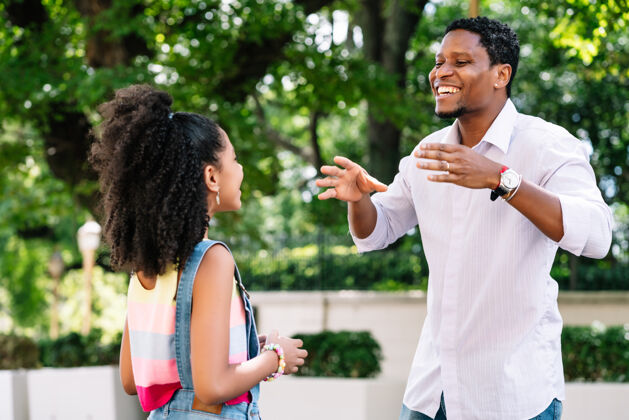 女性一个非洲裔美国小女孩和她的父亲在街上玩得很开心父亲快乐一天