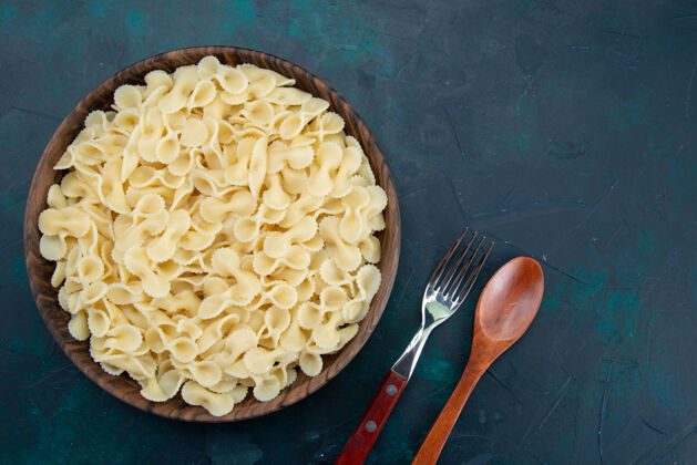意大利面顶视图煮熟的意大利面食在深蓝色的棕色盘子里洋葱配料胡椒