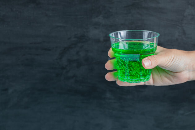 举行手里拿着绿色饮料 里面有水泡玻璃新鲜酒精