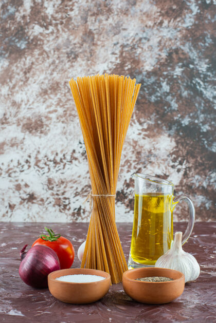 生的生意大利面 橄榄油和新鲜蔬菜放在大理石表面番茄料理调味品