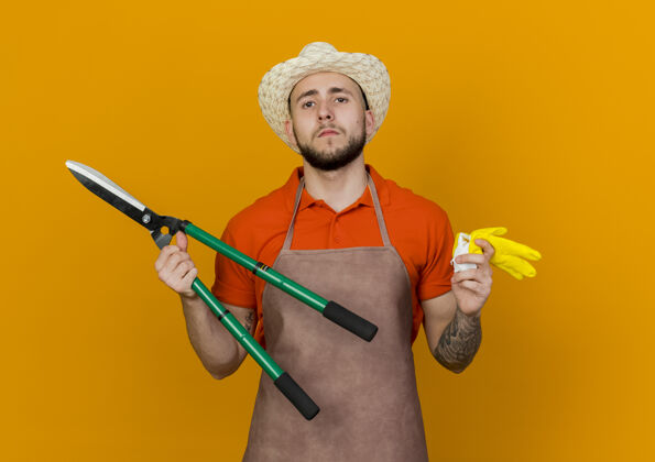 空间自信的男园丁戴着园艺帽拿着剪刀和手套橙色手套园艺