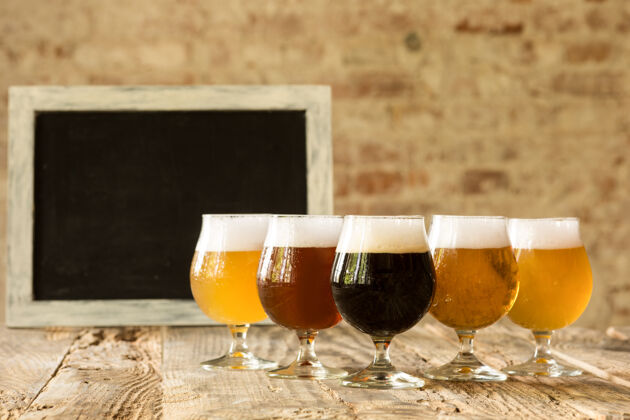 啤酒木桌上摆着各种深浅啤酒的玻璃杯排成一行玻璃泡沫食物