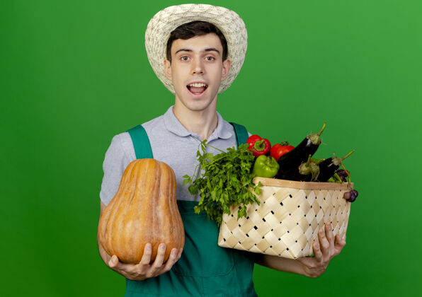 蔬菜快乐的年轻男园丁戴着园艺帽 手里拿着菜篮和南瓜喜悦穿复制