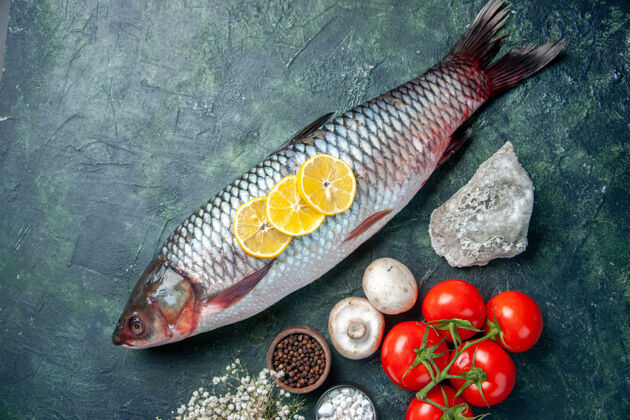 肉顶视图新鲜的生鱼肉与西红柿和柠檬在深蓝色的背景深色视图晚餐