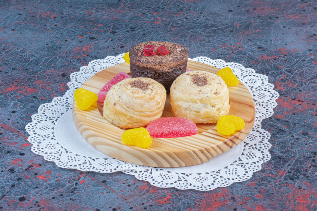 Doily把一捆蛋糕和果酱放在抽象桌上的木盘上糖风味拼盘