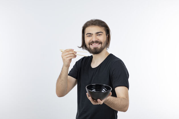 男性一个留胡子的男人拿着筷子在白色的墙上拿着碗年轻人模型摆姿势