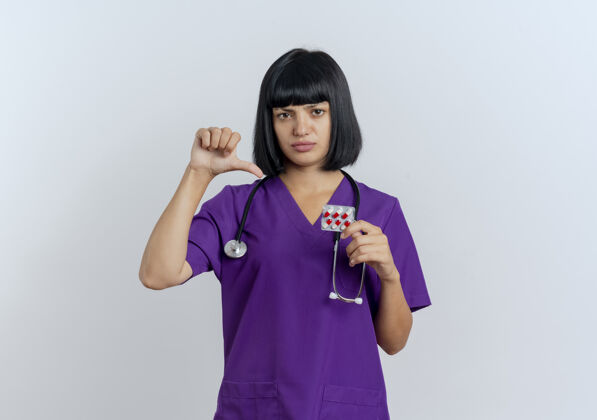 不愉快年轻的黑发女医生穿着制服 手持听诊器指着药黑发副本女性