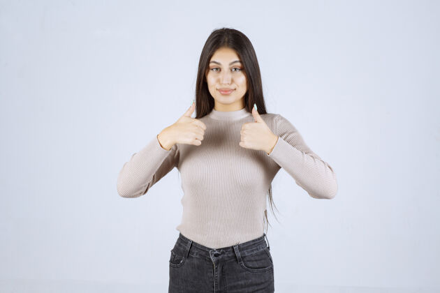 员工穿灰色衬衫的女孩在做竖起拇指的招牌人体模特成人年轻人