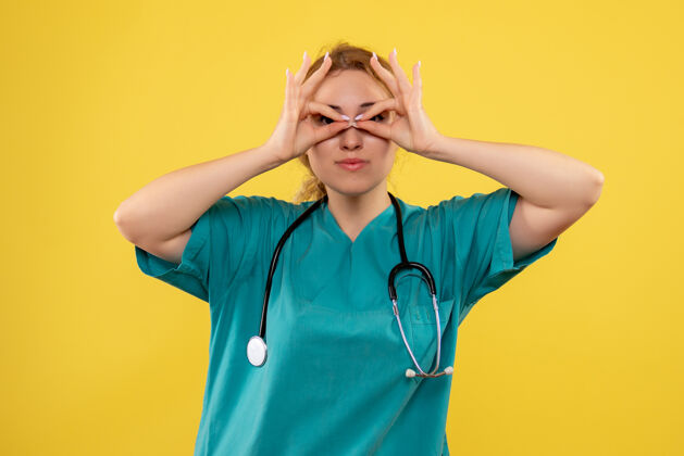 医疗黄色墙上穿着带听诊器的医疗服的女医生的正视图人人听诊器