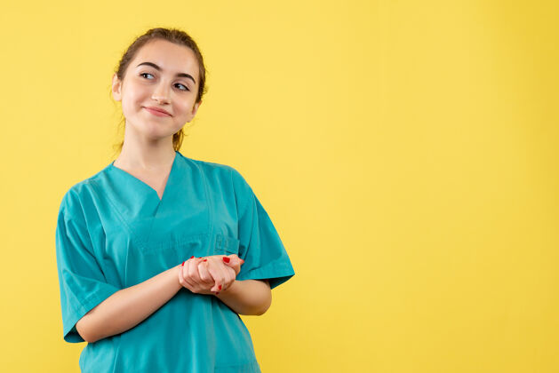 健康黄墙上年轻女医生身着医疗服的正面图成人人工作