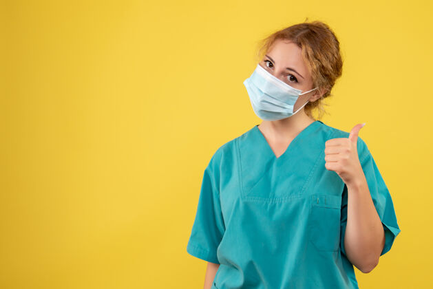 医院黄色墙壁上穿着医疗服 戴着无菌口罩的年轻女医生的正视图人人医生