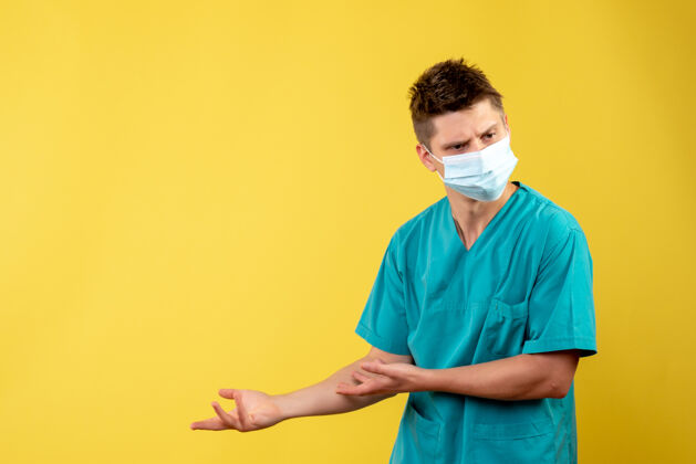 疾病黄墙上带无菌口罩的男医生的前视图男人人面具