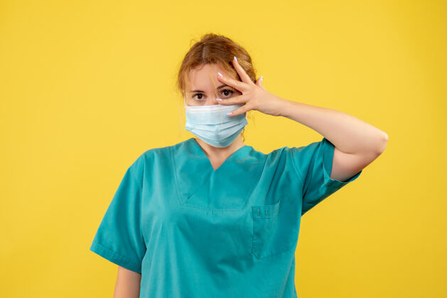 面具黄墙上年轻女医生穿着医疗服 戴着口罩的正面图健康年轻女医生男性